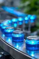 Glowing blue glass jars arranged in curved line on reflective surface create magical ambient lighting effect with soft bokeh and depth of field for party decoration.