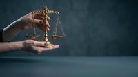 Hands holding golden scales of justice symbol representing law, legal system, court proceedings, attorney services, and judicial balance on dark background.