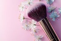 Luxurious makeup brush with soft bristles surrounded by delicate white cherry blossoms on pink background, feminine beauty and cosmetics concept.