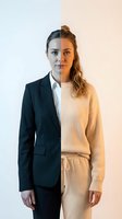 Young professional woman in split business casual attire showing work-life balance concept with formal suit and cozy sweater on contrasting background.
