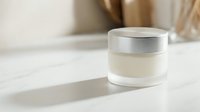 Luxury skincare cream jar with silver cap on marble surface in minimalist bathroom setting with natural lighting and neutral tones for beauty products.