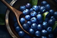 Fresh blueberries in wooden spoon with green leaves on dark background for healthy eating and organic food concepts.