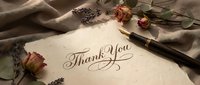 Elegant thank you card with calligraphy on textured paper surrounded by dried roses and lavender sprigs with vintage fountain pen on soft fabric background.
