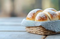 Fresh homemade dinner rolls dusted with powdered sugar in woven basket with checkered napkin on rustic wooden table, soft natural lighting and blurred background.