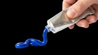 Tube of blue paint or glue being squeezed out onto white surface. Isolated on transparent background, ready for design use on t-shirts, stickers, clipart, and print-on-demand products.