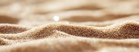 Smooth golden sand dunes with gentle waves and soft texture under warm sunlight, creating a serene desert or beach landscape.