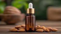 Amber glass dropper bottle with almond oil surrounded by fresh almonds on wooden surface. Natural skincare and aromatherapy product for beauty treatments.