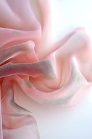 Soft pink silk fabric with gentle folds and waves creating an elegant abstract texture. Delicate light and shadows enhance flowing curves and graceful movement.