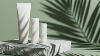 Cosmetic skincare product tubes on stone platform with tropical leaf shadow on sage green background for beauty branding.
