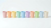 Row of colorful pastel cups arranged on white background for kitchen design and tableware concepts.