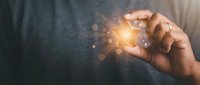 Hand holding glowing light bulb with sparkling bokeh effects representing innovation, creativity, and bright ideas for business presentations.