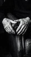 Aged wrinkled hands of an elderly person resting on a leather chair, black and white close-up conveying wisdom, life experience, and the passage of time.