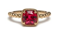 Elegant gold ring with cushion-cut ruby gemstone set in ornate bezel, featuring textured beaded band for luxury jewelry design.