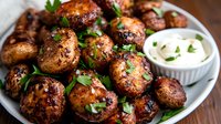 Grilled mushrooms with herbs and spices served on white plate with creamy dipping sauce, garnished with fresh parsley. Restaurant quality appetizer on wooden table.