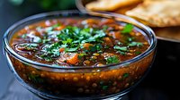 Hearty lentil soup with fresh herbs and vegetables in glass bowl, nutritious comfort food for healthy eating and meal preparation.