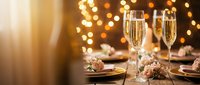 Elegant dinner table setting with champagne flutes and warm bokeh lights creating festive atmosphere for celebration, wedding, or holiday dining.