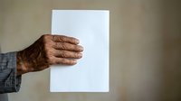 Mature man with dark skin tone holding blank white paper sheet, suitable for mockups, presentations, advertising campaigns, and business communications.