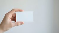 Hand holding blank white business card against neutral background, ready for custom branding and corporate identity design projects.