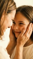 Loving grandmother gently touching granddaughter face in tender moment showing family bond and intergenerational connection in warm natural light.