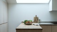 Modern minimalist kitchen interior with wooden countertop, fresh salad bowl, cutting board and natural skylight illumination for contemporary home design.