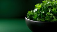 Fresh organic parsley leaves in dark ceramic bowl against green background with copy space, selective focus on aromatic culinary herbs.