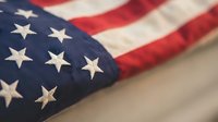 American flag with stars and stripes folded ceremonially on neutral background representing patriotism, freedom, and national pride for Memorial Day.