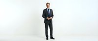 Caucasian male professional in dark business suit and tie standing confidently against white background, suitable for corporate, business, and corporate training materials.