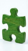 Green wooden puzzle piece with textured surface and natural grain pattern, standing upright on white background for business, teamwork, and problem-solving concepts.
