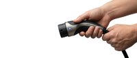 Male hands holding black electric vehicle charging cable connector on white background isolated for automotive technology design.