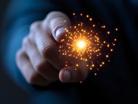 Male hand holding glowing magical light sphere with sparkling particles against dark background, representing innovation and creative energy concept.