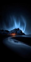 Dramatic aurora borealis dancing over snow-capped mountain peaks and curved shoreline at twilight creating mystical atmosphere for nature photography.