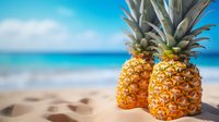 Fresh tropical pineapples on sandy beach with turquoise ocean background, summer vacation and exotic fruit concept for healthy lifestyle and travel.
