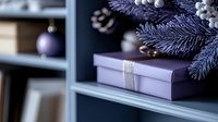 Purple wrapped gift box with silver ribbon under frosted pine branches and Christmas ornaments on blue shelf, creating elegant holiday atmosphere.