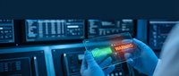 Young male technician in blue gloves examining transparent smartphone with holographic warning alert display in data center control room environment.