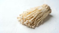 Enoki mushrooms isolated on white background, fresh edible fungi with delicate thin stems and small caps, ready for culinary and food design use.
