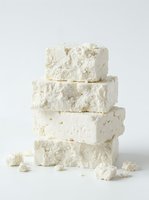 Stacked white feta cheese blocks isolated on neutral background, showcasing crumbly texture and fresh dairy product for culinary, food styling, and restaurant menu design use.