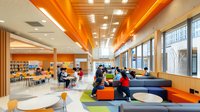 Modern school library interior with students studying at colorful seating areas and wooden ceiling design for educational architecture concepts.