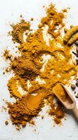 Turmeric powder scattered on white surface with wooden scoop containing golden spice, suitable for culinary, wellness, and food styling projects.