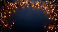 Glowing orange fairy lights creating magical border frame against dark blue background, festive holiday decoration with copy space for text or design.