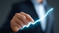 Businessman pointing at glowing blue arrow graph trending upward on dark background, representing business growth, success and financial performance analysis.