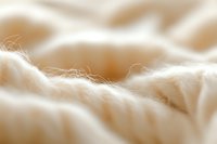 Soft beige wavy textile surface in macro photography showing delicate fabric texture and gentle folds with smooth bokeh effect and warm lighting.