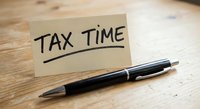 Tax time reminder note with black pen on wooden desk for accounting and financial planning preparation.