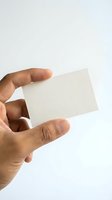 Hand holding blank cream business card against white background, ready for custom branding and contact information design.