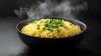 Steaming hot ramen noodles garnished with fresh chopped green onions in black ceramic bowl against dark background, rising vapor creates dramatic effect.