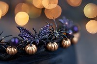 Glittery purple butterfly decoration with metallic gold pumpkins on dark background, illuminated by warm bokeh lights creating magical autumn ambiance.