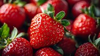 Fresh ripe strawberries with green leaves close up macro shot showing detailed texture of juicy red berries in natural daylight, food photography.