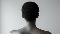Black and white portrait showing back view of African American person's head and shoulders against light background, creating minimalist artistic composition.