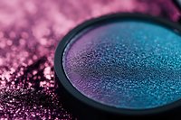 Shimmering duochrome eyeshadow palette with purple and teal gradient colors in round compact for makeup and beauty applications.