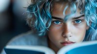 Young person with vibrant blue dyed hair and intense blue eyes reading book in soft natural lighting, creating atmospheric mood for lifestyle and youth culture content.
