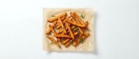 Golden crispy sweet potato fries seasoned with herbs on parchment paper, healthy alternative to regular fries for restaurant menus and food blogs.